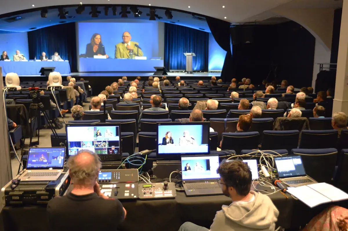 Régie vidéo installée au fond d’un auditorium pendant une assemblée retransmise sur grand écran